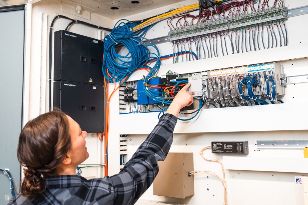 In Control staff inspecting a control panel and its electrical connections
