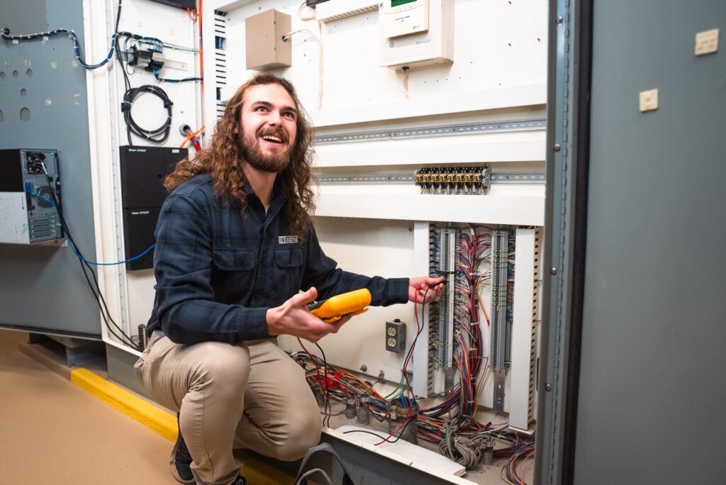 In Control technician inspecting connections inside a control cabinet